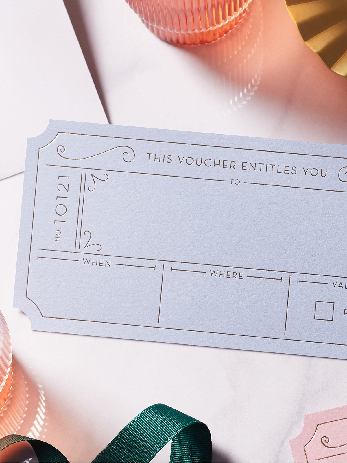 Chalk Blue Golden Ticket voucher with Hot Foiled in gold , green ribbon around it on a white background