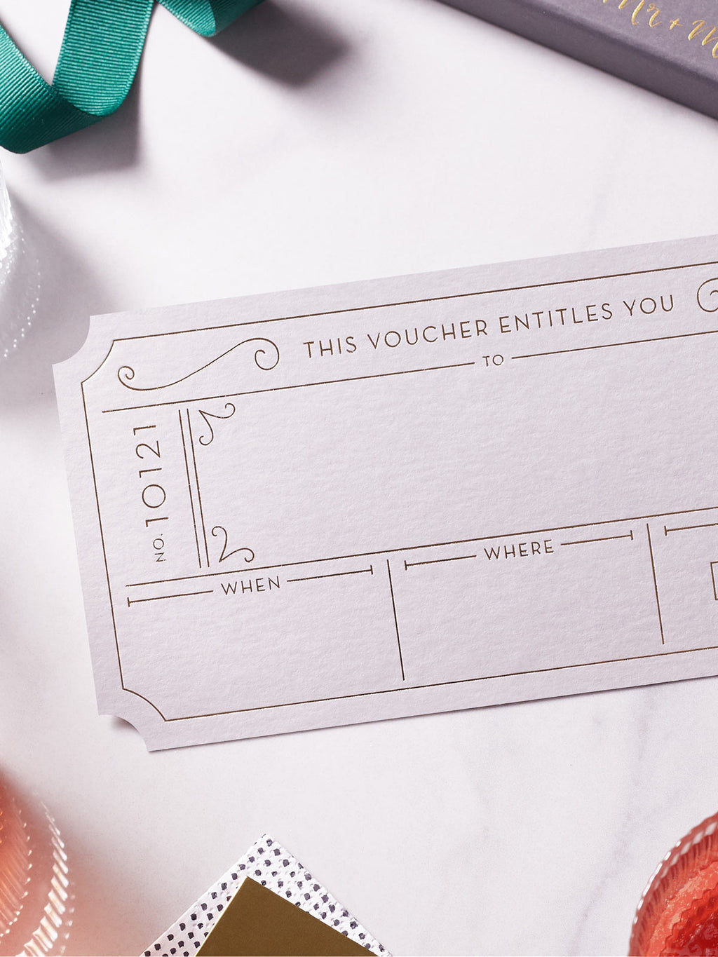 Plume Grey Golden Ticket voucher with Hot Foiled in gold , green ribbon around it on a white background