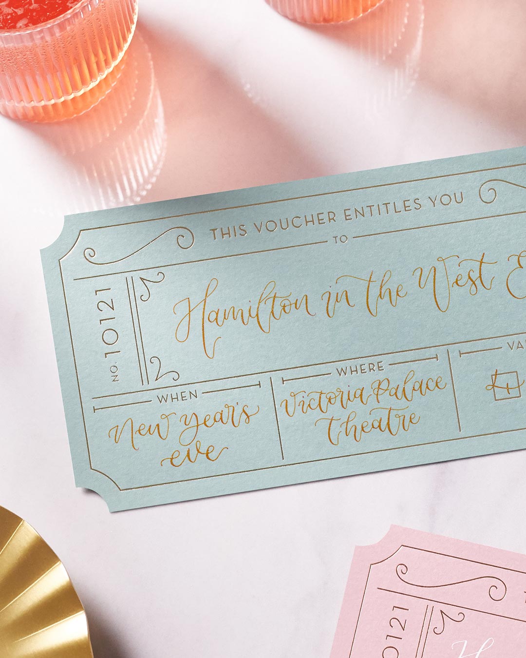 green event ticket with gold foil on a marble tabletop, personalised with modern calligraphy to create a bespoke golden ticket