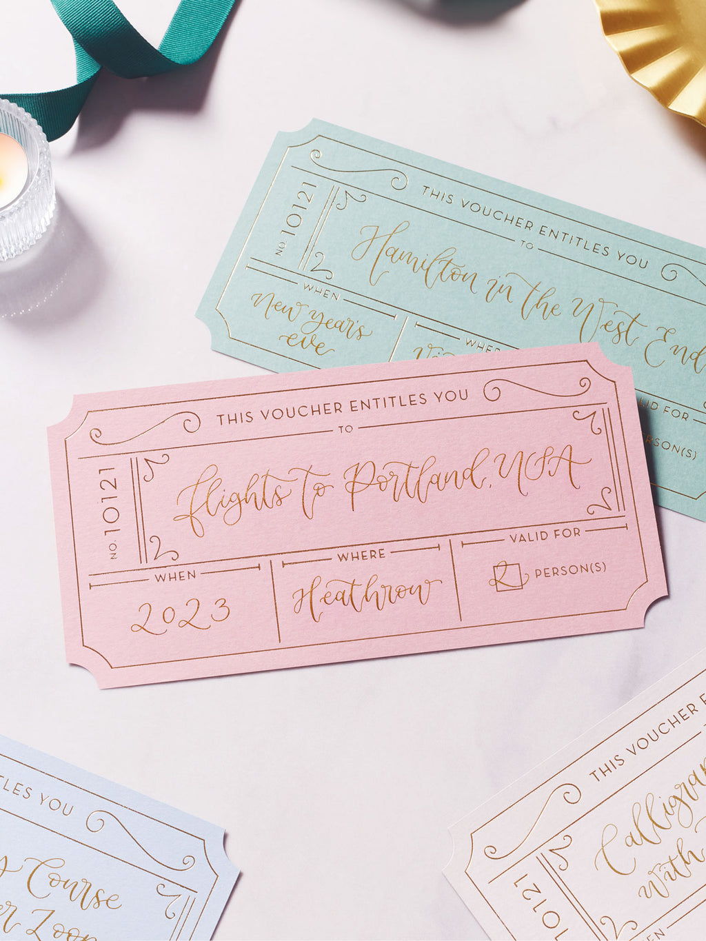 selection of gift vouchers with gold foil on a marble tabletop, personalised with modern calligraphy to create bespoke golden tickets