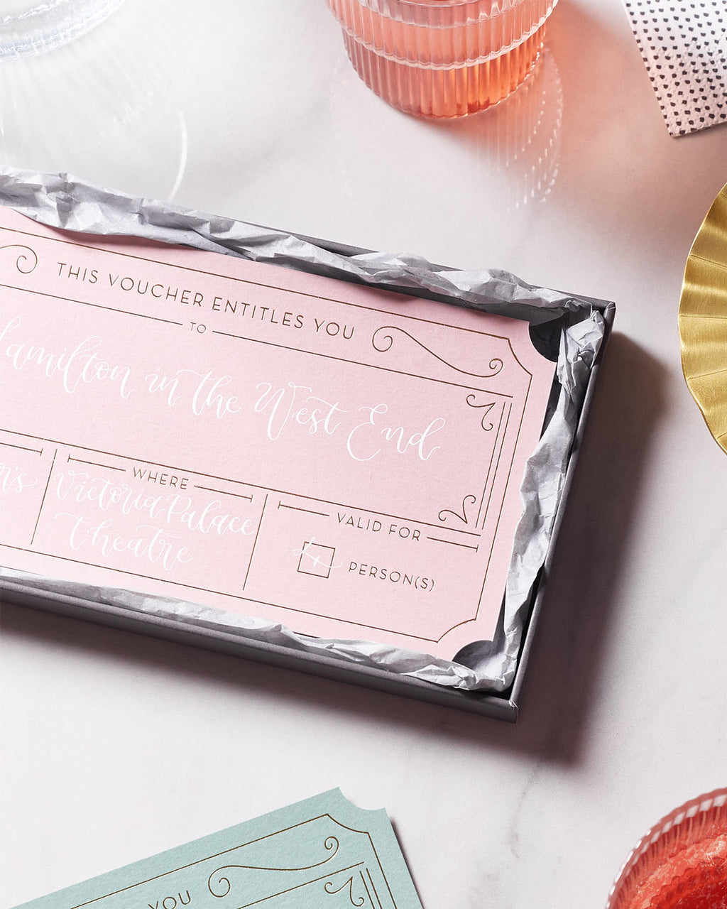 half open gift box revealing a pink golden ticket personalised with modern calligraphy